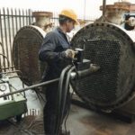 man-working-on-heat-exchanger-with-tools